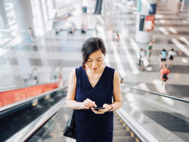 Gambar Wanita dengan smartphone di tangga berjalan